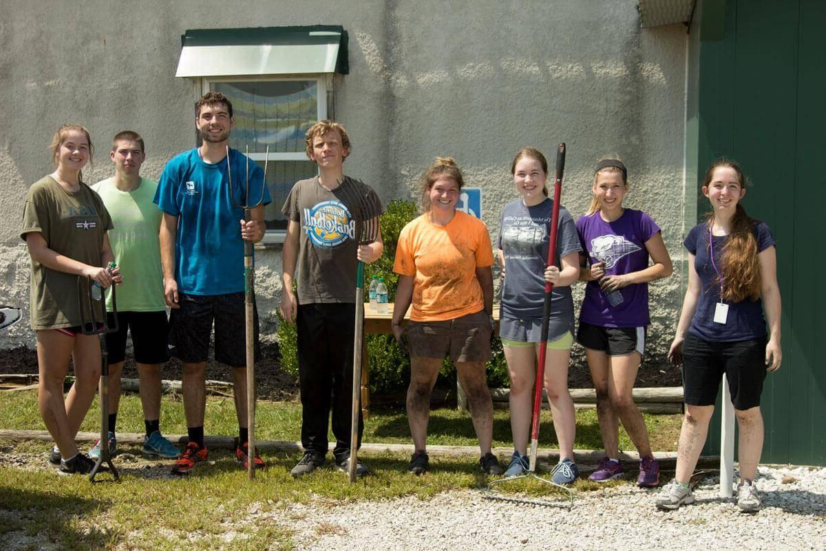 一组八名学生在为服务项目做庭院工作时摆姿势拍照